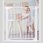 Vit barngrind i metall monterad i dörröppning, med litet barn stående bakom grinden för att visa säkerheten