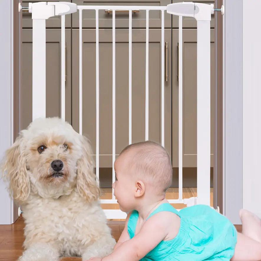 Vit barngrind i metall installerad i dörröppning, med baby och liten hund framför grinden som visar säker avdelning mellan rum