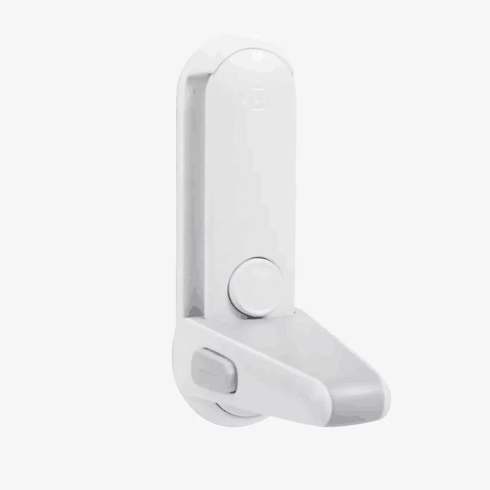 Vitt barnlås för dörrhandtag med en nedfälld spärrarm. Låset har en rund knapp på framsidan och en vinklad spärrdel nederst som hindrar dörrhandtaget från att tryckas ned.