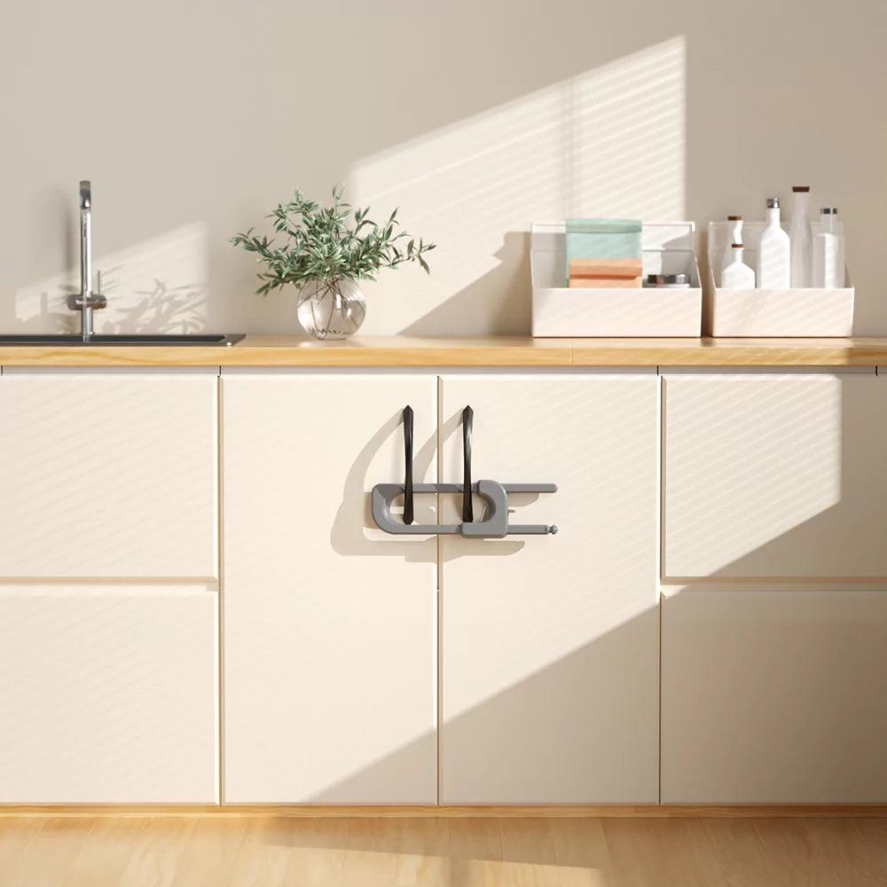 Grått barnlås för dubbeldörr med handtag monterat på köksskåp för att hindra barn från att öppna skåpen