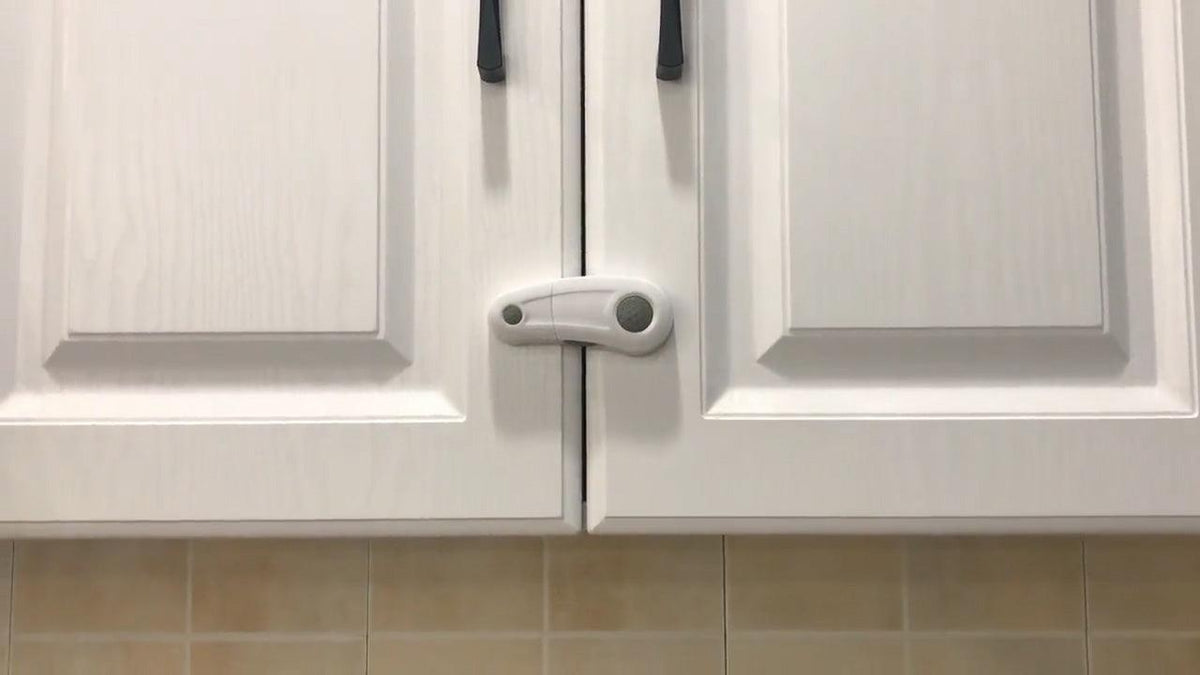 Vitt barnlås monterat på skåp med dubbeldörr för att förhindra att barn öppnar dörrarna.