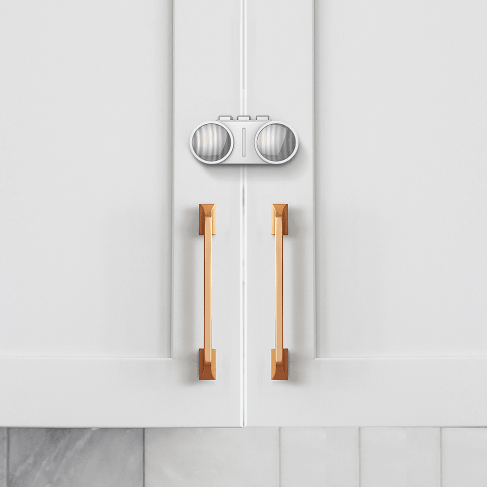 Premium barnlås för dubbeldörrar monterat på vit skåpslucka med handtag.