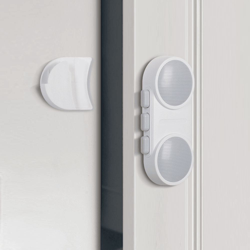 Premium barnlås för dubbeldörrar monterat på skåpskant i vit plast.