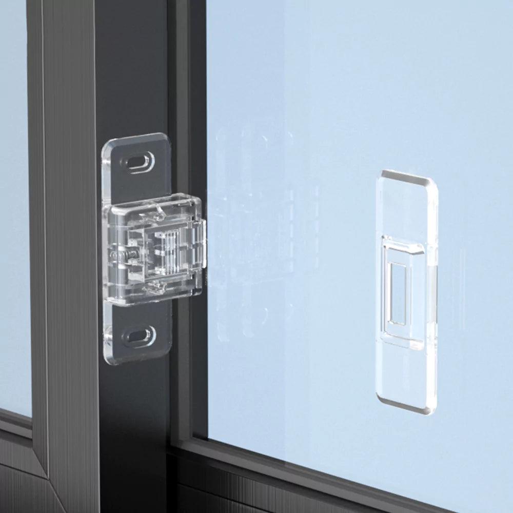 Transparent barnsäkert lås monterat på en skjutdörr av glas med fäste på båda sidor.”