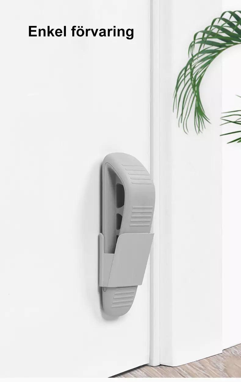 En grå dörrkil sitter upphängd i en väggmonterad hållare på en vit dörr, med texten ”Enkel förvaring” ovanför.