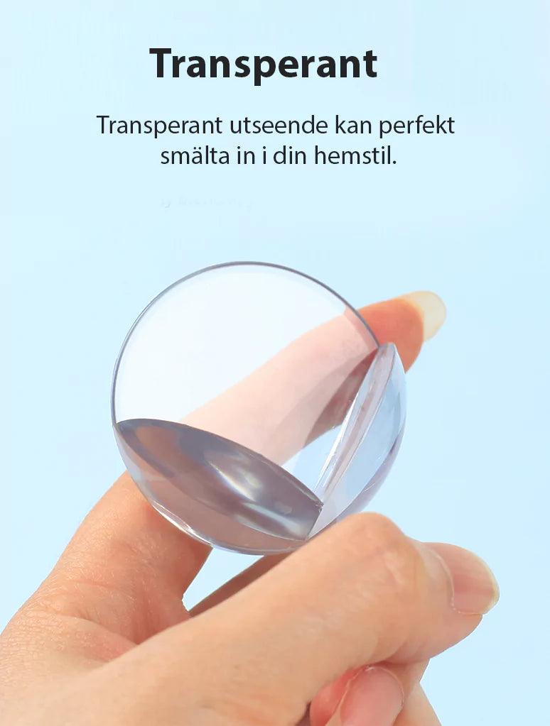 Transparent hörnskydd i mjukt material som hålls mellan fingrarna och visar sin diskreta, genomskinliga design.