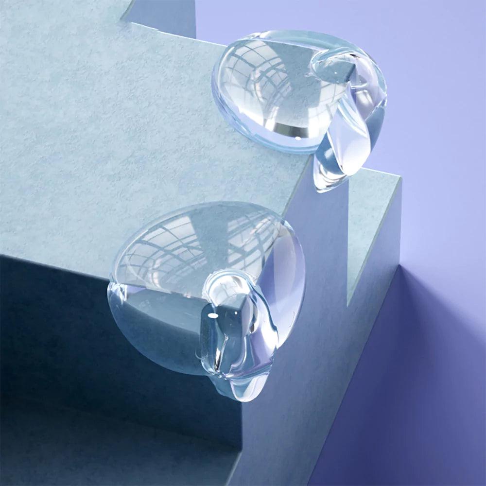 Transparenta extra skyddande hörnskydd i silikon monterade på blå kantiga möbelhörn, visade i närbild.