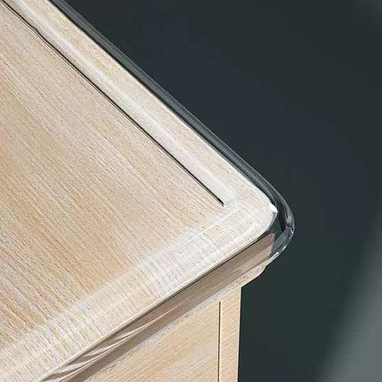 Transparent kantskydd monterat längs kanten på en ljus träbordsskiva för att skydda mot vassa hörn.