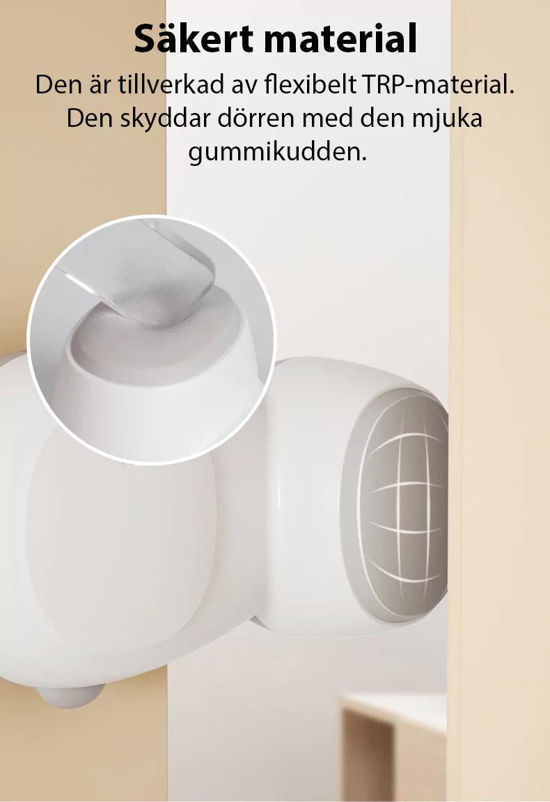 Ett vitt dörrklämskydd av flexibelt TRP-material monterat på en dörrkarm. Bilden visar den mjuka gummikudden som skyddar dörren när skyddet roterar och tar emot trycket vid öppning.