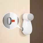 Vitt automatiskt klämskydd monterat på dörrkarmen, med en detaljinzoomning som visar den lilla aktiveringsknappen markerad med en röd pil.