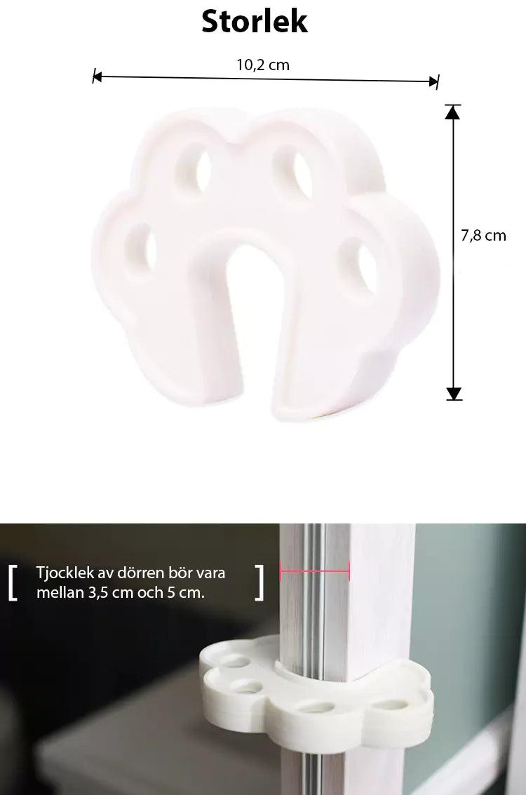 Vitt blomformat dörrklämskydd i skum med måtten 10,2 × 7,8 cm, visat både ensamt och monterat på en dörrkant. Passar dörrar med tjocklek mellan 3,5 och 5 cm.