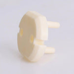 Närbild av ett barnsäkert petskydd för eluttag i EU-typ, visat i vinkel med två plaststift och rund frontplatta i beige ABS-material.