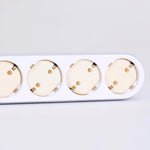 Flera vägguttag med monterade barnsäkra petskydd i ljus plast, placerade i en vit grenpropp av EU-typ.