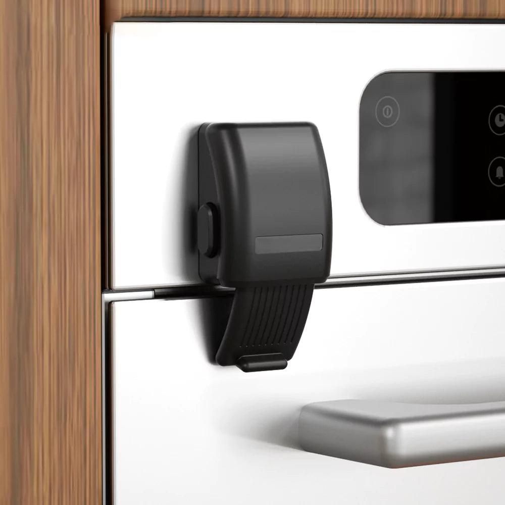 Svart barnsäkert ugnslås monterat på vit ugnslucka för att förhindra att barn öppnar ugnen