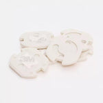 Vita vridbara petskydd för eluttag med självhäftande 3M-tejp, staplade i en grupp.