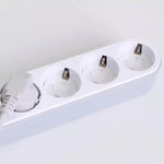 Förlängningsdosa med flera eluttag där vridbara petskydd sitter monterade, och ett av uttagen används av en ansluten elkontakt.