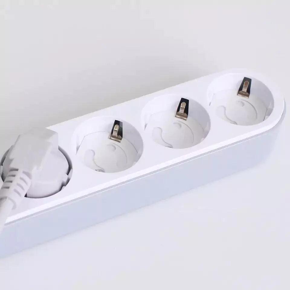 Förlängningsdosa med flera eluttag där vridbara petskydd sitter monterade, och ett av uttagen används av en ansluten elkontakt.